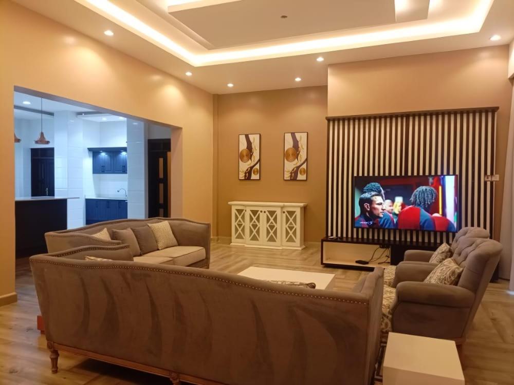 a living room with two couches and a flat screen tv at DAVE's LIVING in Kampala