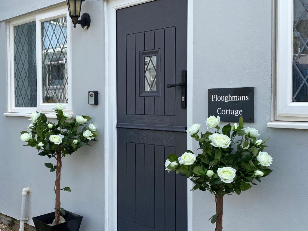 a black door with flowers in front of a house at Ploughmans Cottage, St Florence, Tenby in Saint Florence
