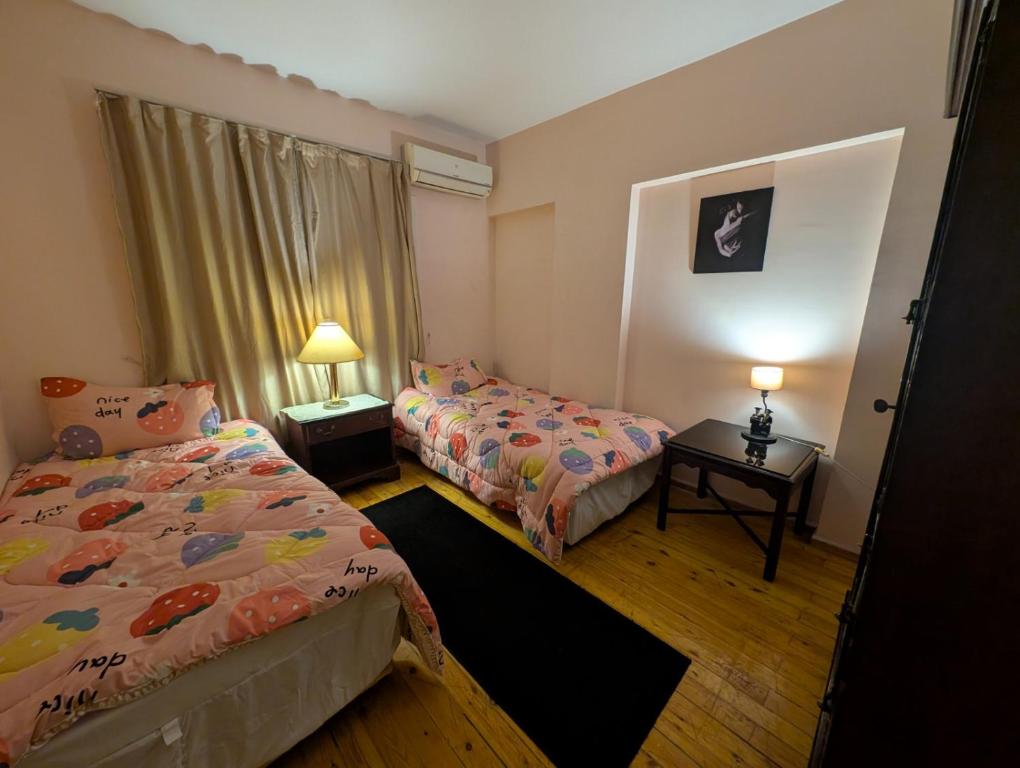a bedroom with two beds and a table with lamps at Tango Violin in Cairo