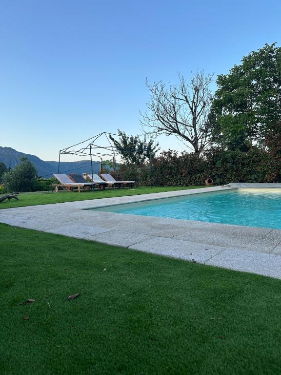 a swimming pool in a yard with a sidewalk and grass at Casa Ermida in Pincães