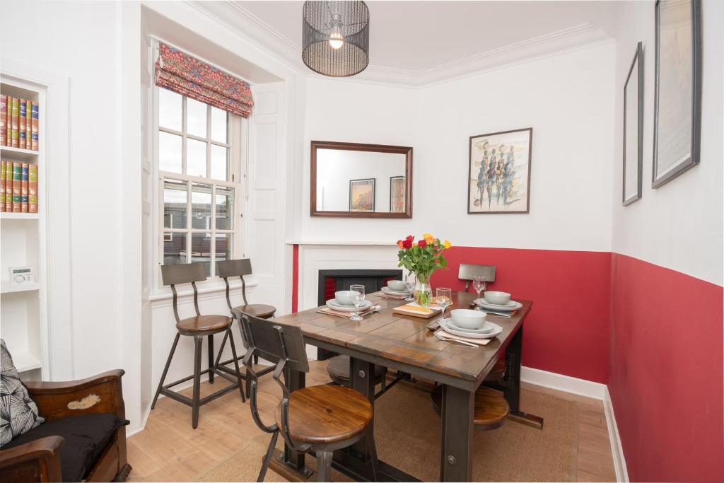 a dining room with a table and a red accent wall at Banrigh House in Stirling