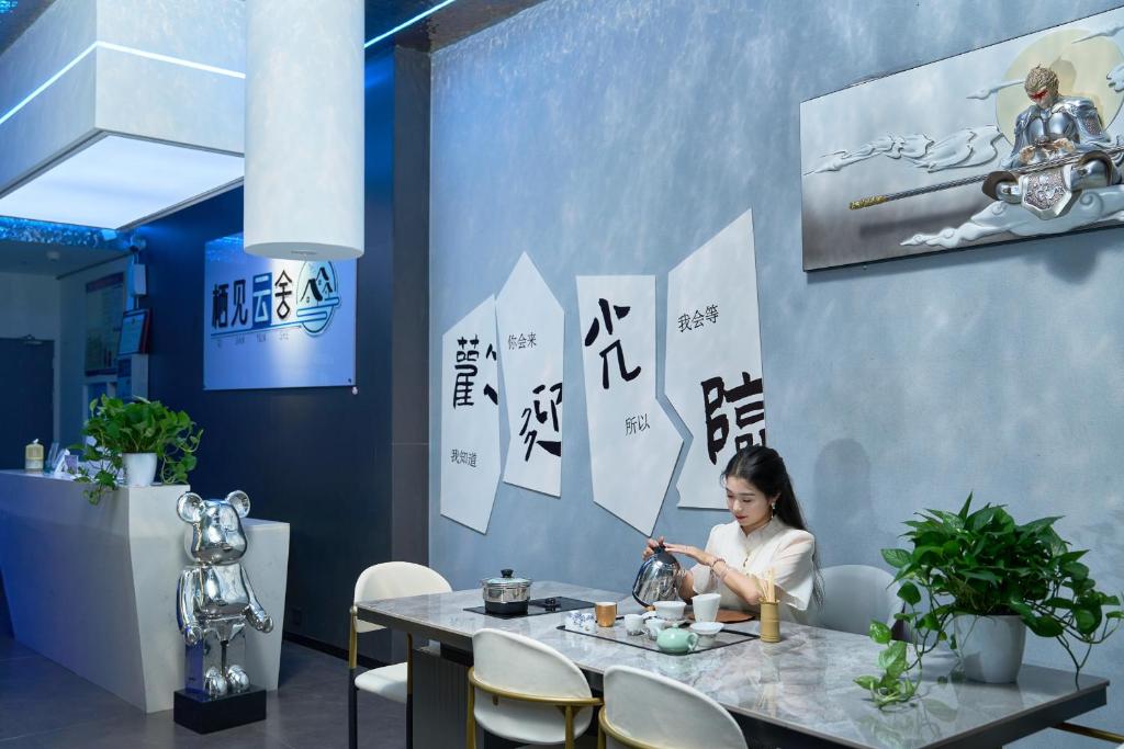a woman sitting at a table in a restaurant at ZhangJiaJieWuLingYuan栖见云舍Hotel in Hanqiyu
