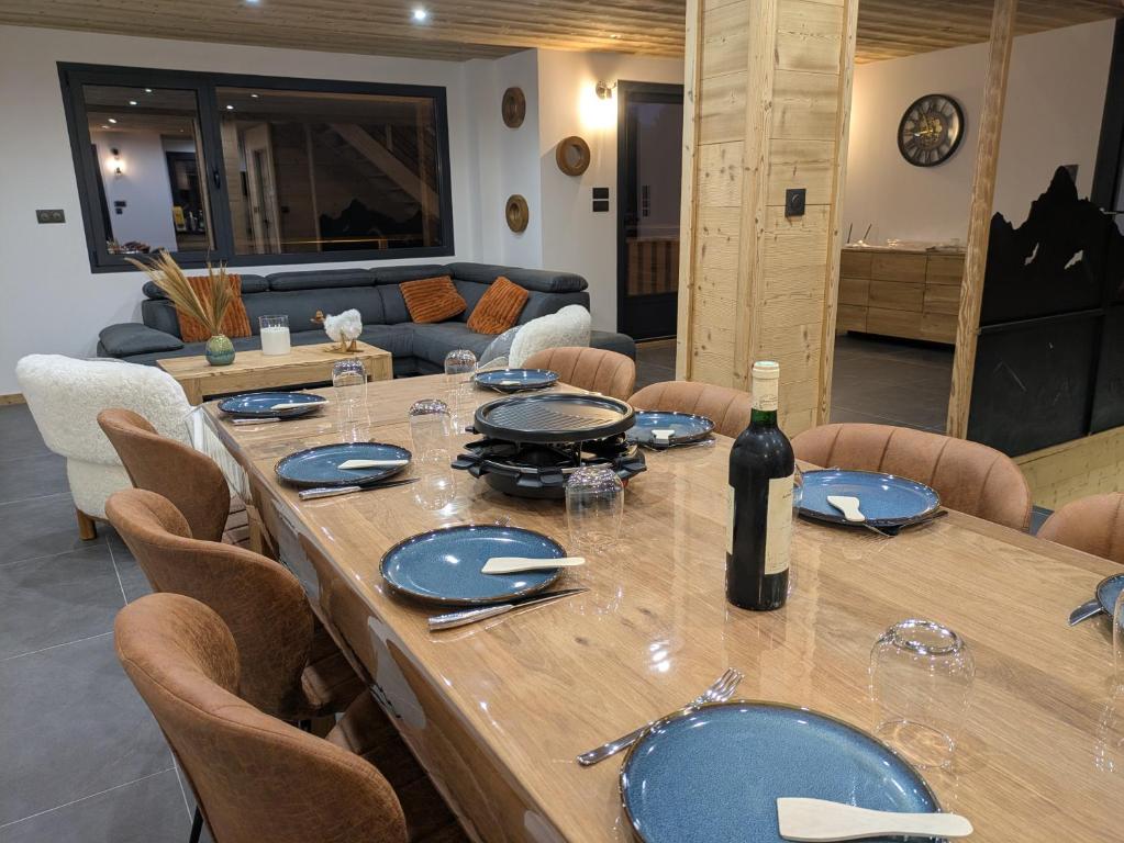 een grote houten tafel met daarop een fles wijn bij Chalet La Tanière avec Sauna in Le Grand-Bornand