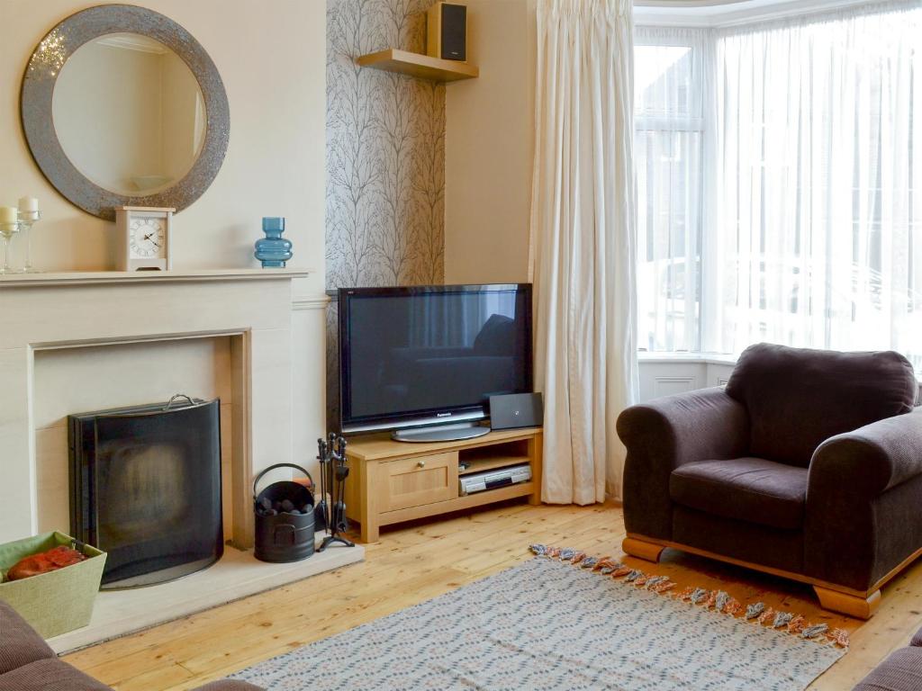 a living room with a television and a chair at Middleton House in Filey