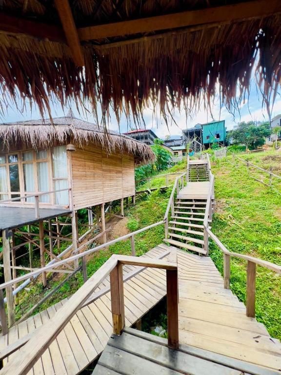 a wooden walkway leading to a building with a grass roof at Meghrani Eco Cottage in Māhmuam