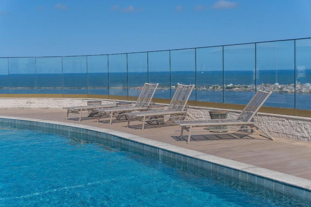 a pool with chairs and tables on a building at Vista mar - Flat Parque do Cais 1211 in Recife