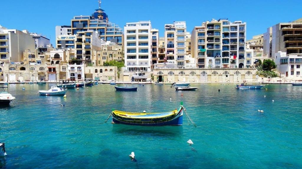 a group of boats in a body of water with buildings at Seafront place Spinola StJulians in St. Julianʼs