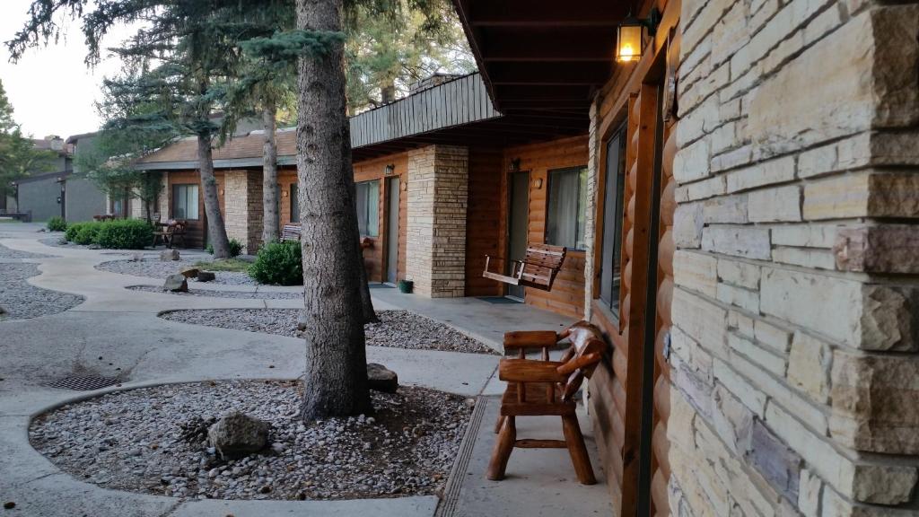a wooden chair sitting outside of a building with a tree at West Winds Lodge in Ruidoso