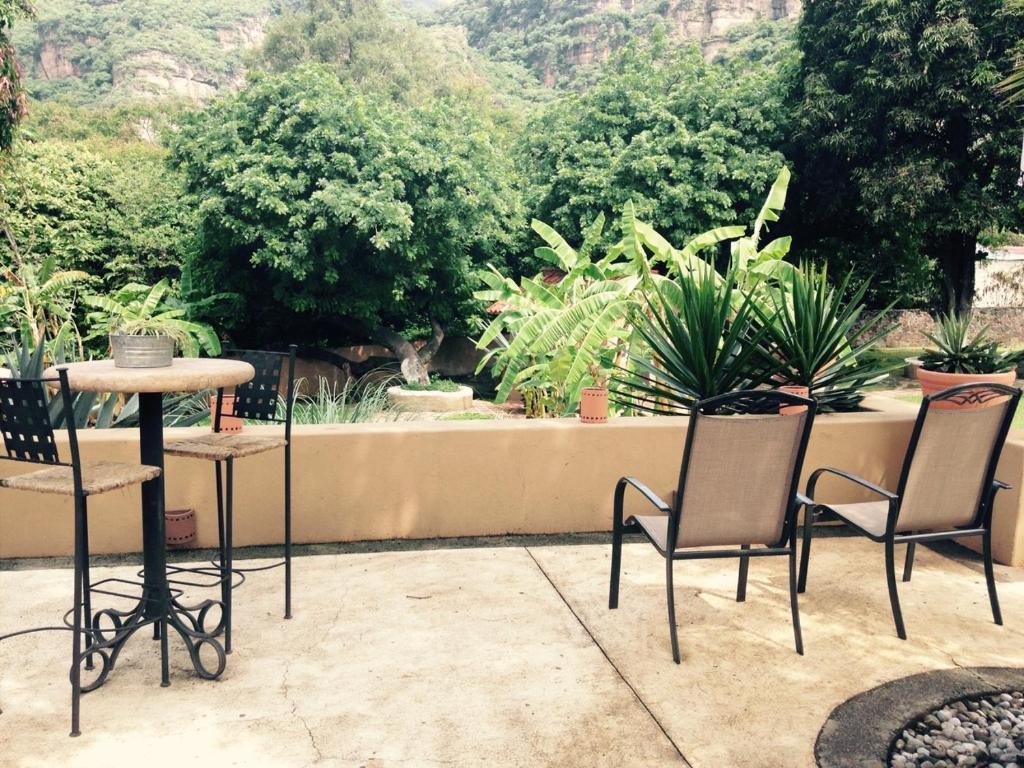 een patio met 3 stoelen en een tafel en planten bij Hotel Boutique Casa de Campo Malinalco in Malinalco