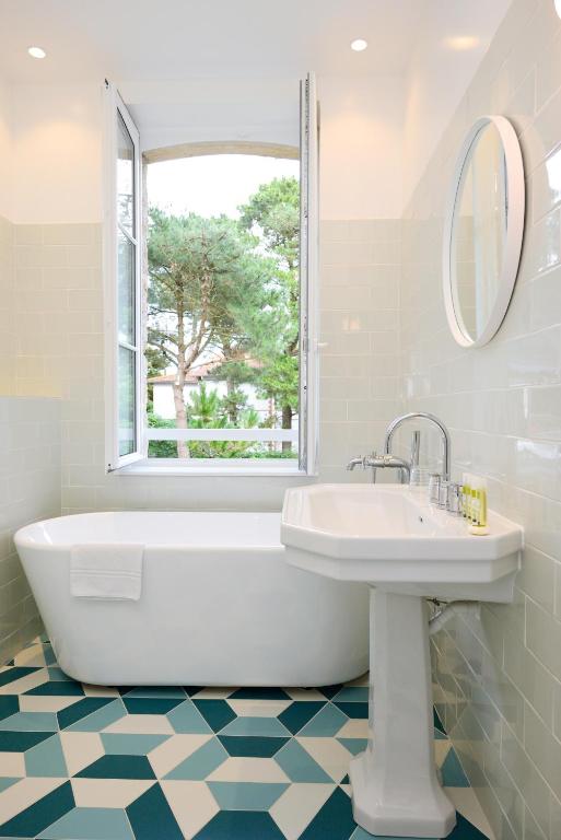a bathroom with a tub and a sink and a window at Hôtel Le Saint Christophe in La Baule
