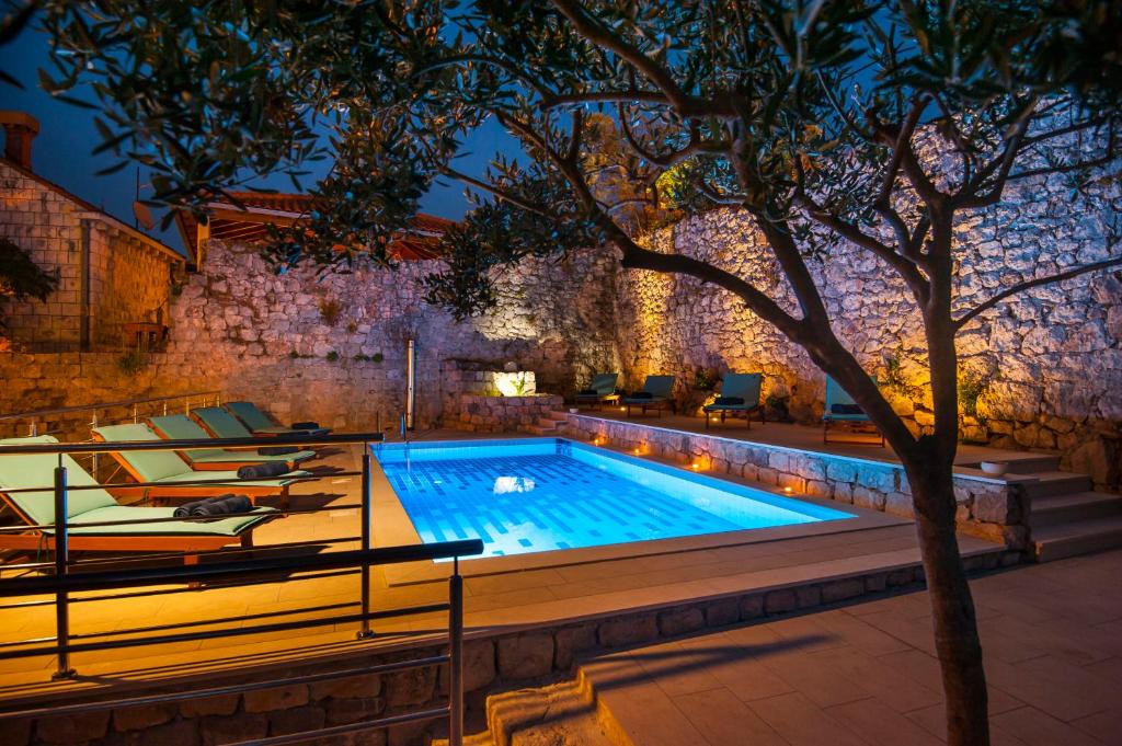a swimming pool with lounging chairs and a tree at California Apartments in Dubrovnik