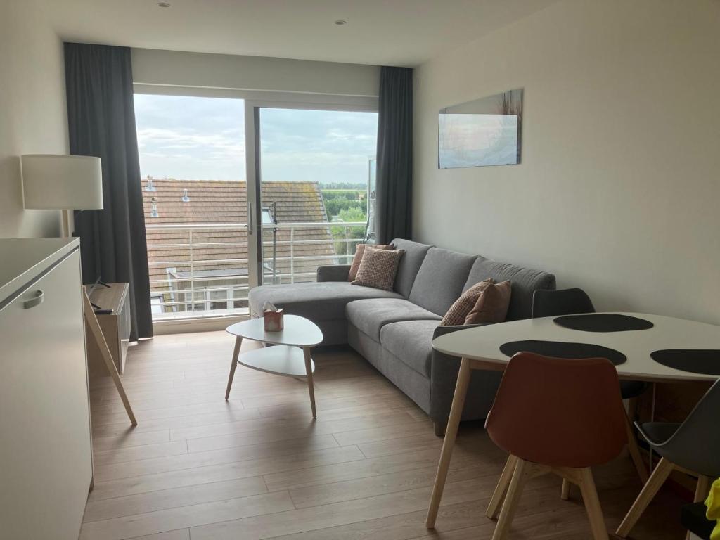 a living room with a couch and a table at Studio Sol Y Mar Westende in Westende Bad