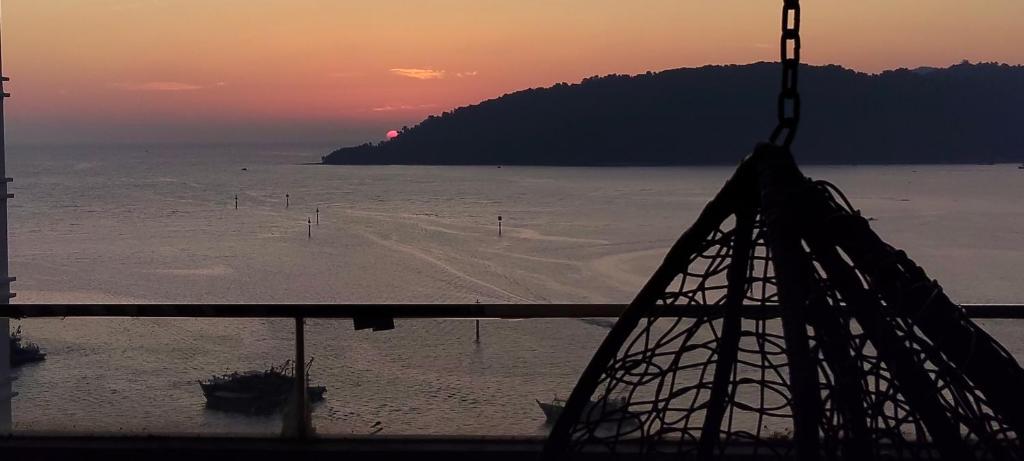 a view of the beach at sunset with a crane at The Shore KK - Seaview Suite with Stunning Sunset & Private Balcony in City Centre in Kota Kinabalu