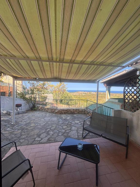 タナウネッラにあるVista Mare Houseの天蓋の下にベンチとテーブルがあるパティオ