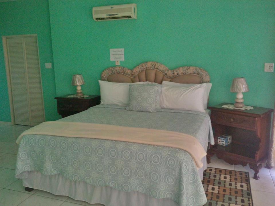 a bedroom with a large bed with green walls at Pinnacle View Estate Tiana Villa in Montego Bay