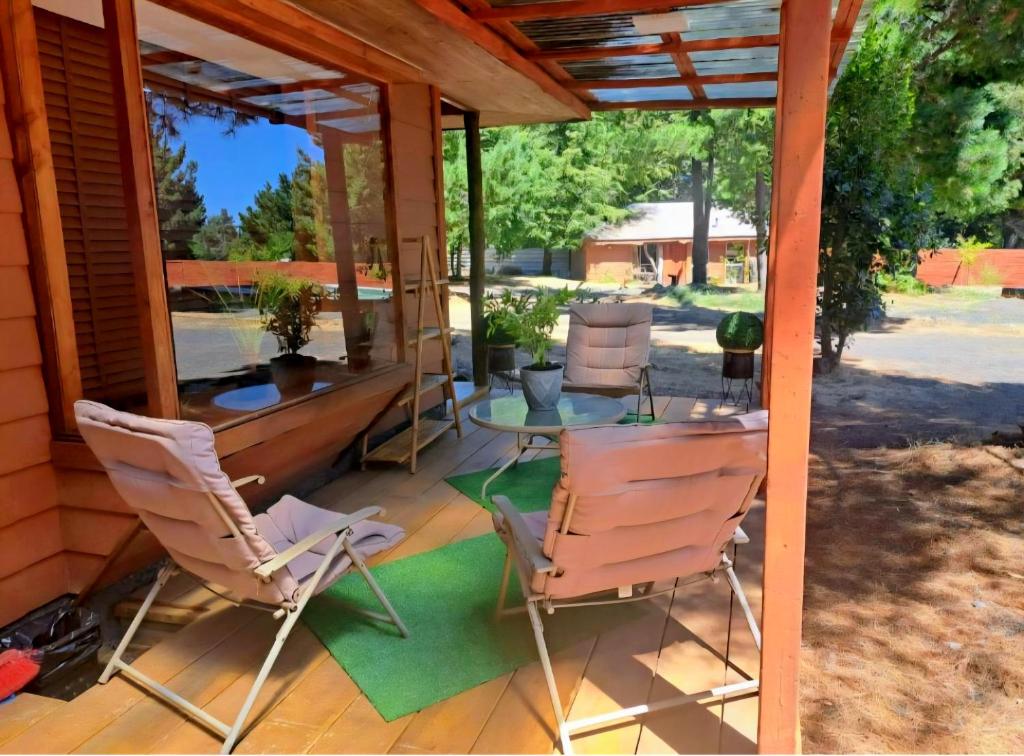 a screened in porch with chairs and a table at Cabañas Torres Del Bosque in Pucón