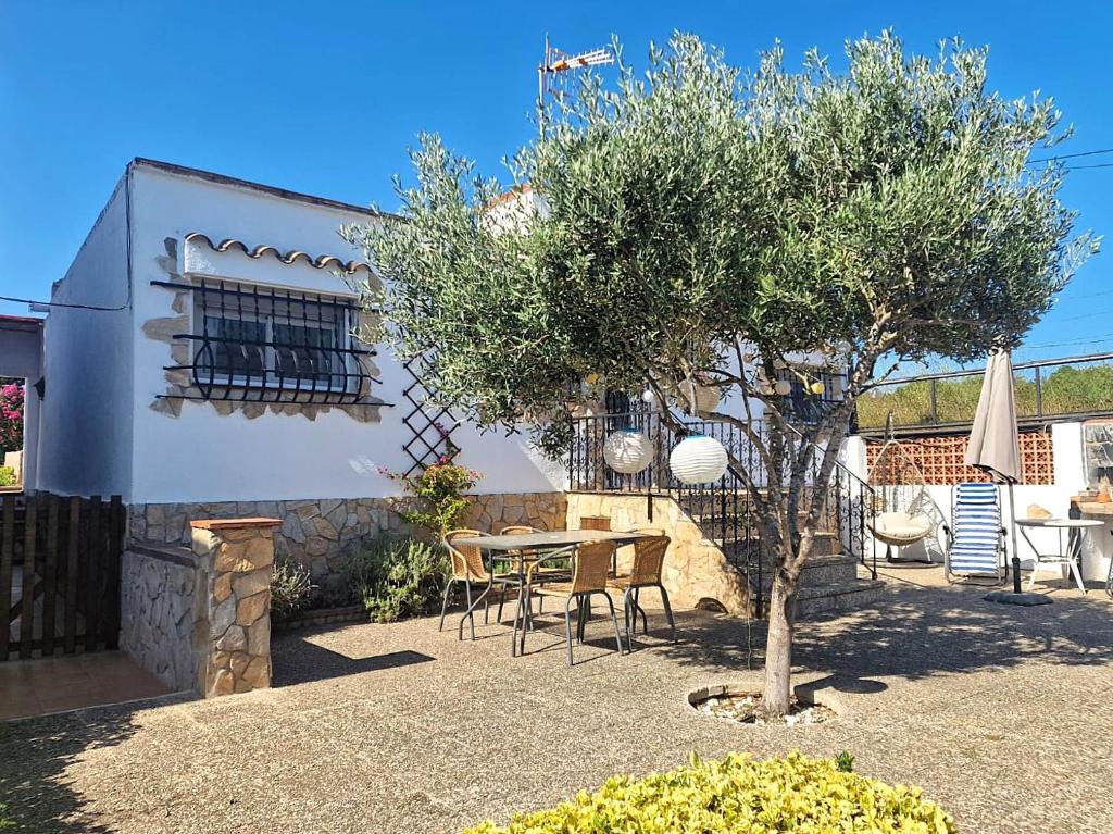 a patio with a table and chairs and a tree at Villa de Gracia Casa 3 in Tordera