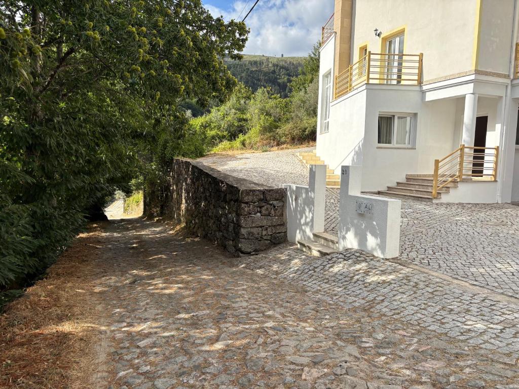 a house with a stone wall next to a building at Casa das Oliveiras - Manteigas in Manteigas