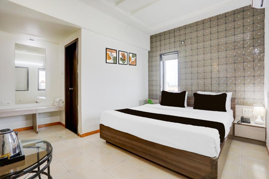 a bedroom with a large bed and a glass table at Hotel O Metro in Rajkot