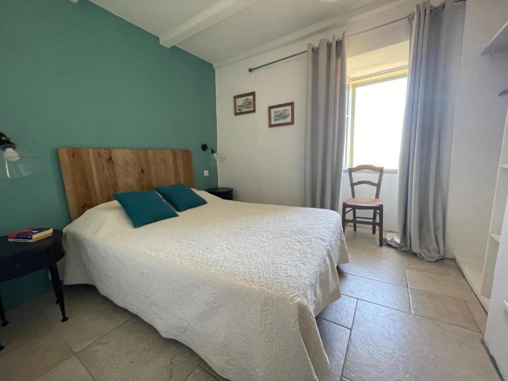 Un dormitorio con una cama y una ventana y una silla. en Maison authentique 4 à 10 personnes, en Ersa