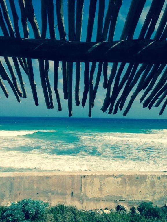 a view of the ocean from under a beach umbrella at House by the beach Casa Murmullos in Isla Mujeres