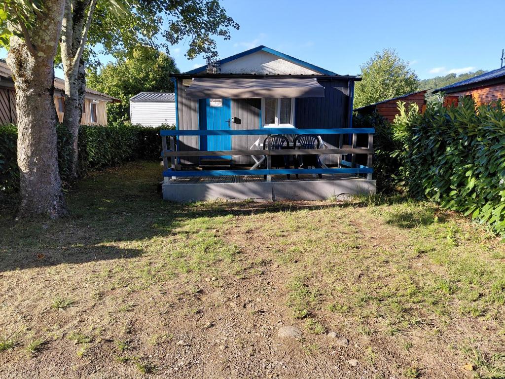 a blue outhouse with a porch in a yard at Petit chalet 5 personnes in La Celle-sous-Gouzon