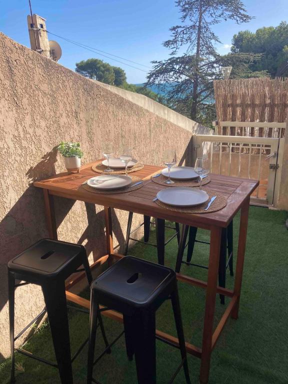 un tavolo in legno con sedie e piatti di Les Alizes Apartment Beachfront a Carry-le-Rouet
