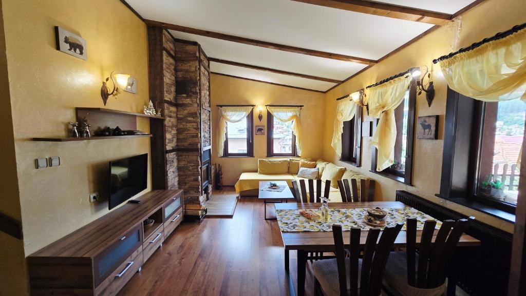 a living room with a dining table and a living room with yellow walls at Guest House Chepelare in Chepelare