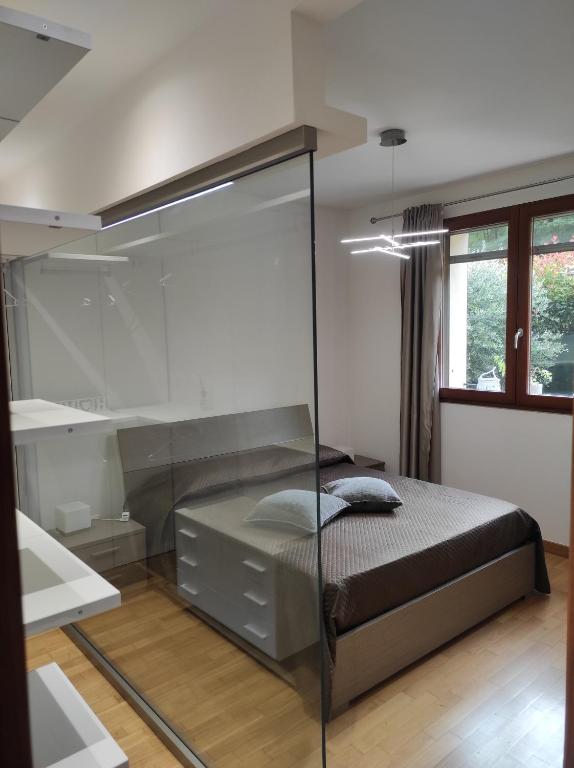 - une chambre avec un lit et une paroi en verre dans l'établissement Giardino Erasmo, à Arona