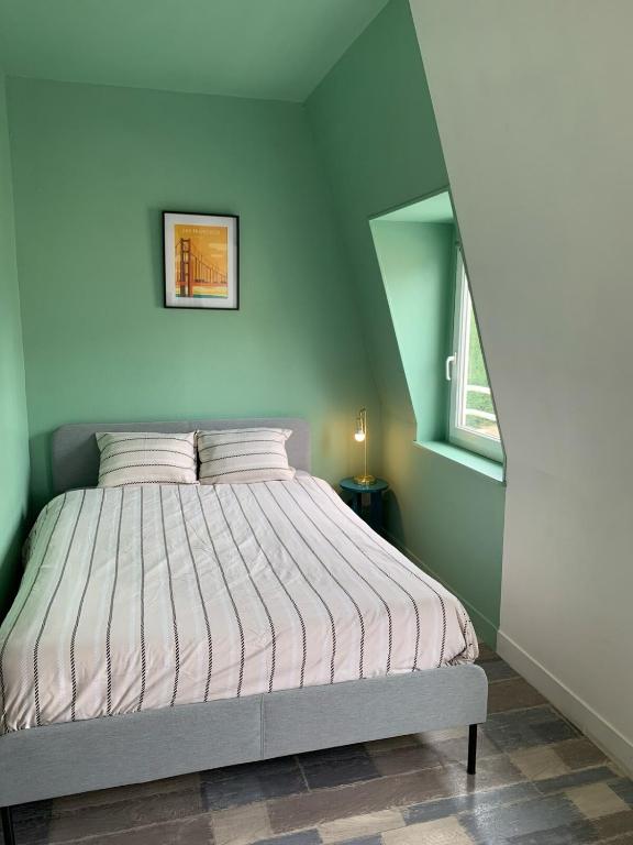 a bedroom with a bed with a striped comforter at Le Jardin du Haras in Saint Lo