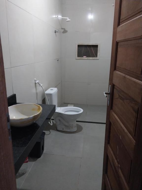 a bathroom with a toilet and a sink and a door at ChacaraSophya in Aquiraz
