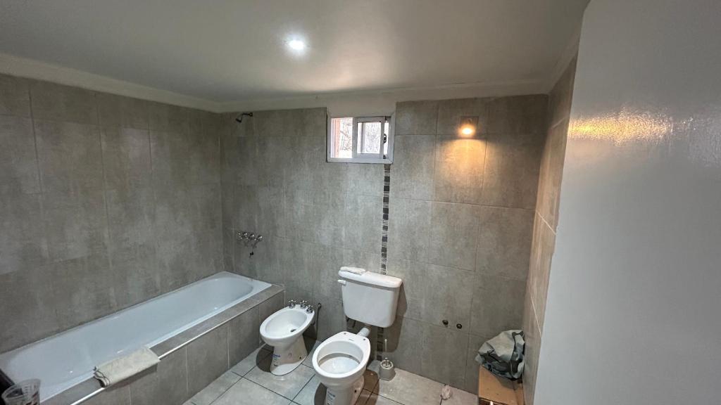 a bathroom with a toilet and a bath tub at Habitación privada con cama matrimonial, baño y salida al jardín in Colonia Las Rosas