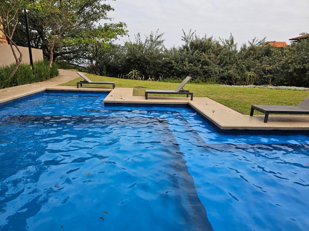 a swimming pool with blue water in a yard at Zimbali Suites 108 in Ballito