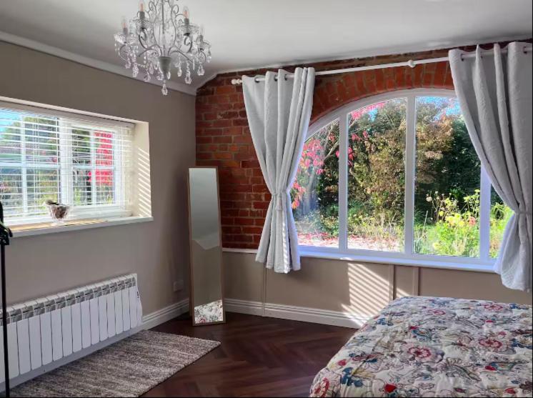 - une chambre avec un lit, 2 fenêtres et un lustre dans l'établissement Honey Cottage, à Boston