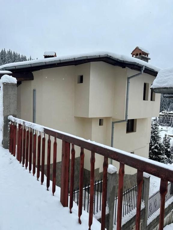 a building with snow on the ground next to a fence at Свети Георги in Stoykite