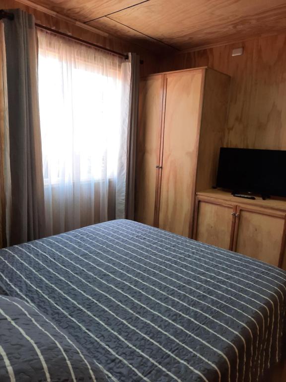 ein Schlafzimmer mit einem Bett und einem Fenster und einem Fernseher in der Unterkunft Cabaña Elizabeth in Cochrane