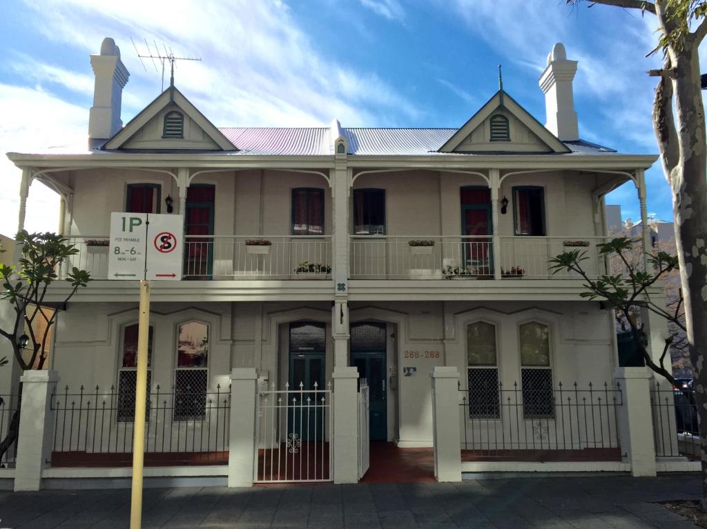 a large white building with a balcony on top at Hay Street Traveller's Inn in Perth