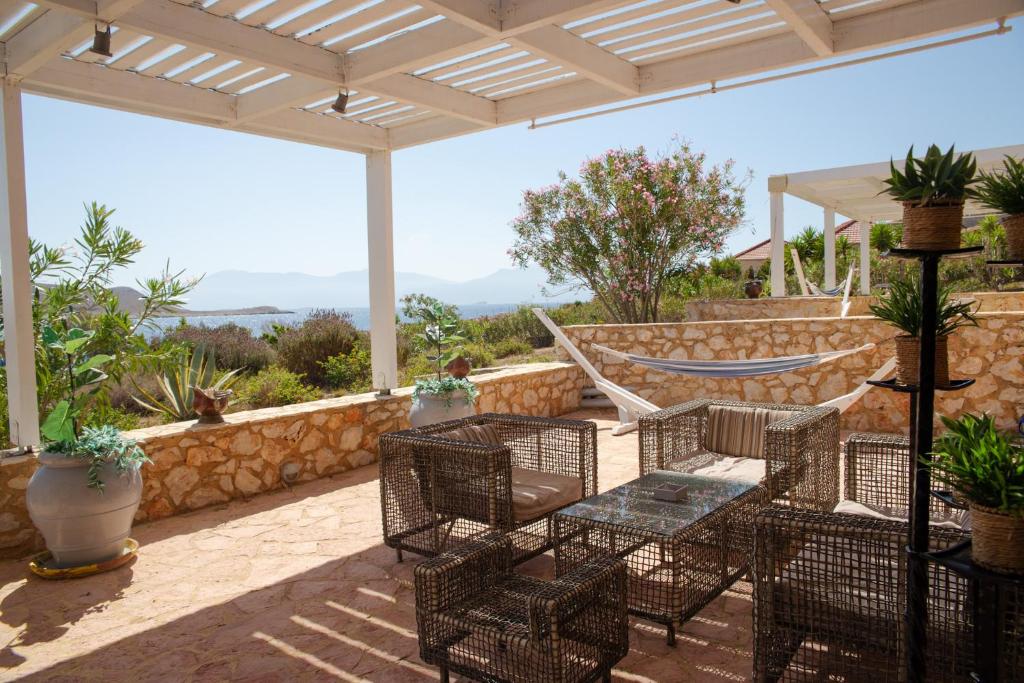 un patio con sillas, una mesa y una hamaca en Belvedere private luxury beach villa, en Halki