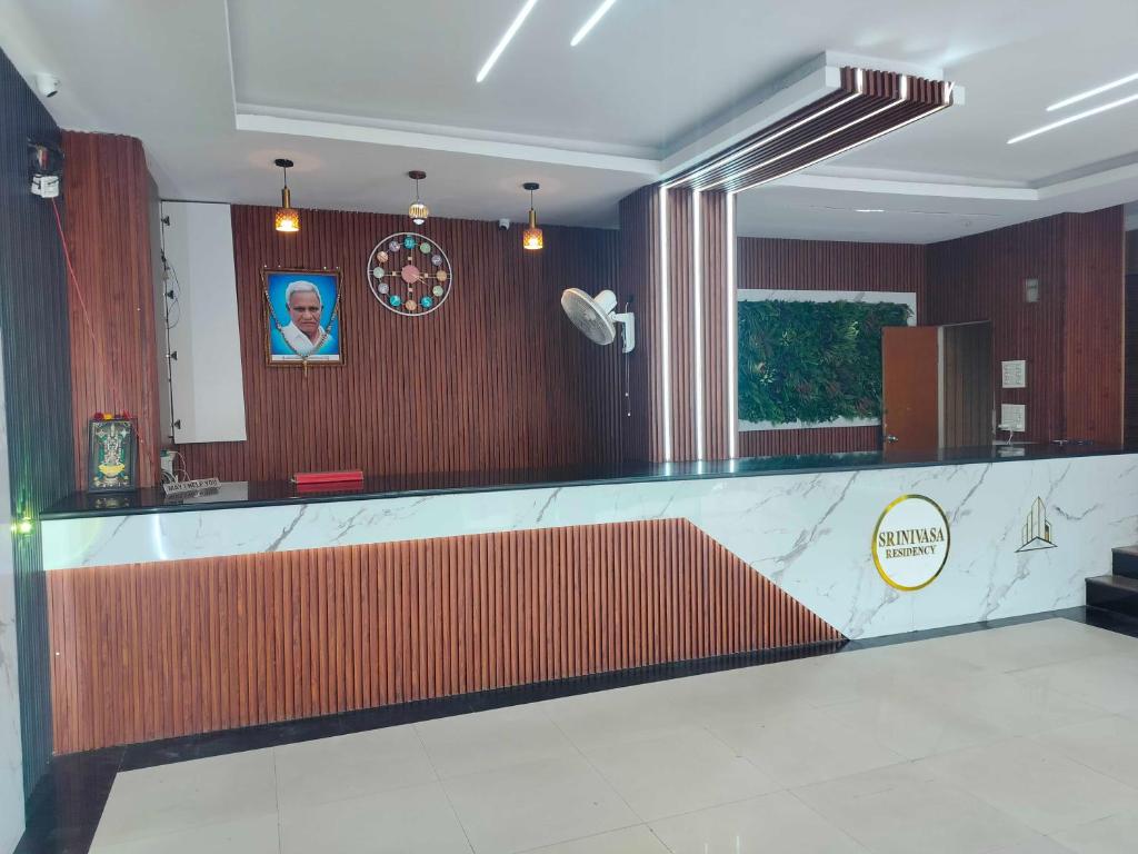 a lobby with a counter with a man on the wall at SPOT ON Srinivasa Residency in Tirupati