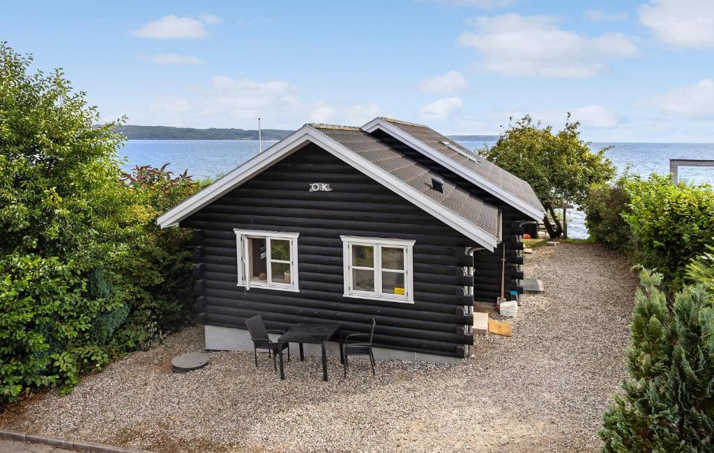 a black house with chairs in front of the ocean at Awesome Home In Børkop With Wifi in Børkop