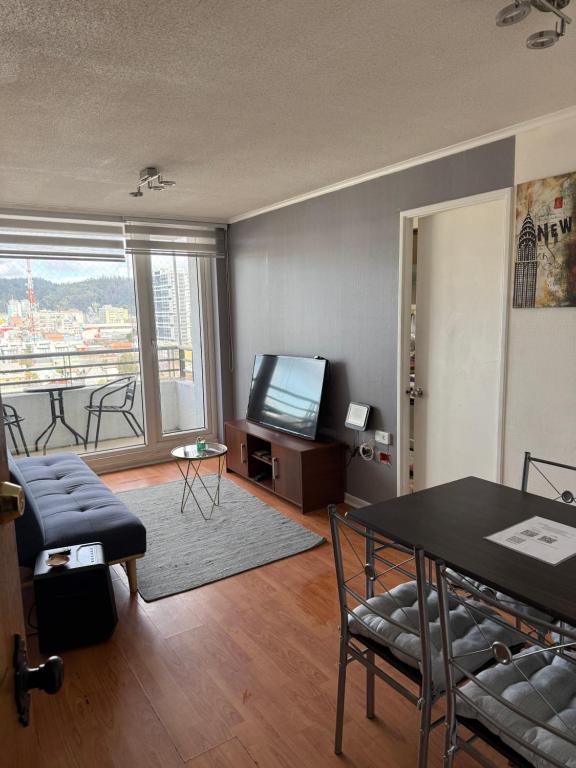 un salon avec une table et une télévision dans l'établissement Vista Mirador Centro con Balcón Dúo, à Concepción