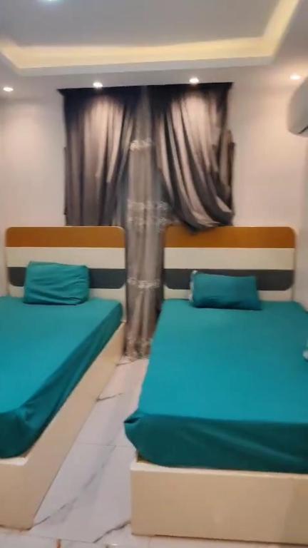two beds in a room with blue sheets and a window at إسراء المهندسين in Cairo