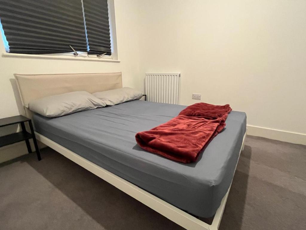 a bed with a red blanket on top of it at Next to Southall Station - Brand new Apartment Room in Southall