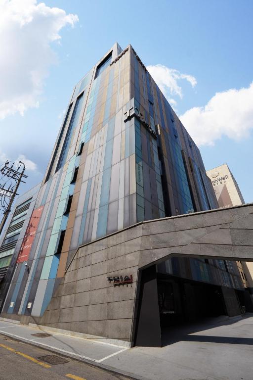 a tall building with glass windows on a street at Tria Business & Boutique Hotel in Seoul