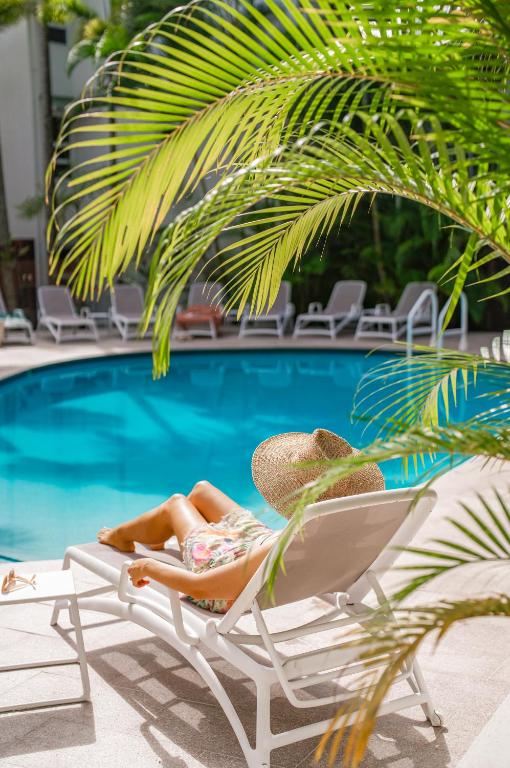 a woman laying in a chair next to a pool at The Lookout Resort Noosa in Noosa Heads