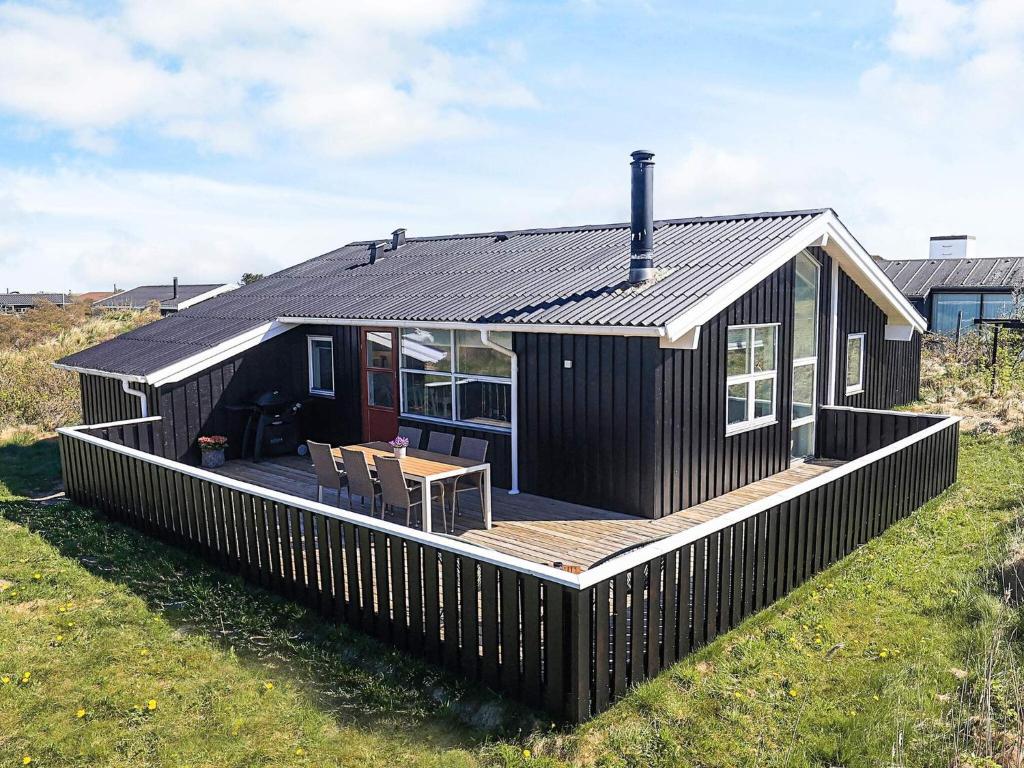 a black house with a deck and a table at 6 person holiday home in Hjørring in Hjørring