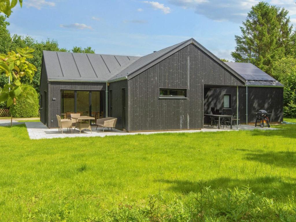 a black barn with a patio and green grass at 10 person holiday home in Glesborg-By Traum in Glesborg