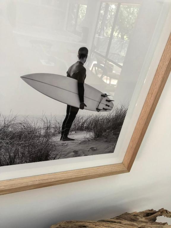 a picture of a man holding a surfboard on a wall at Beachside Phillip Island in Cowes