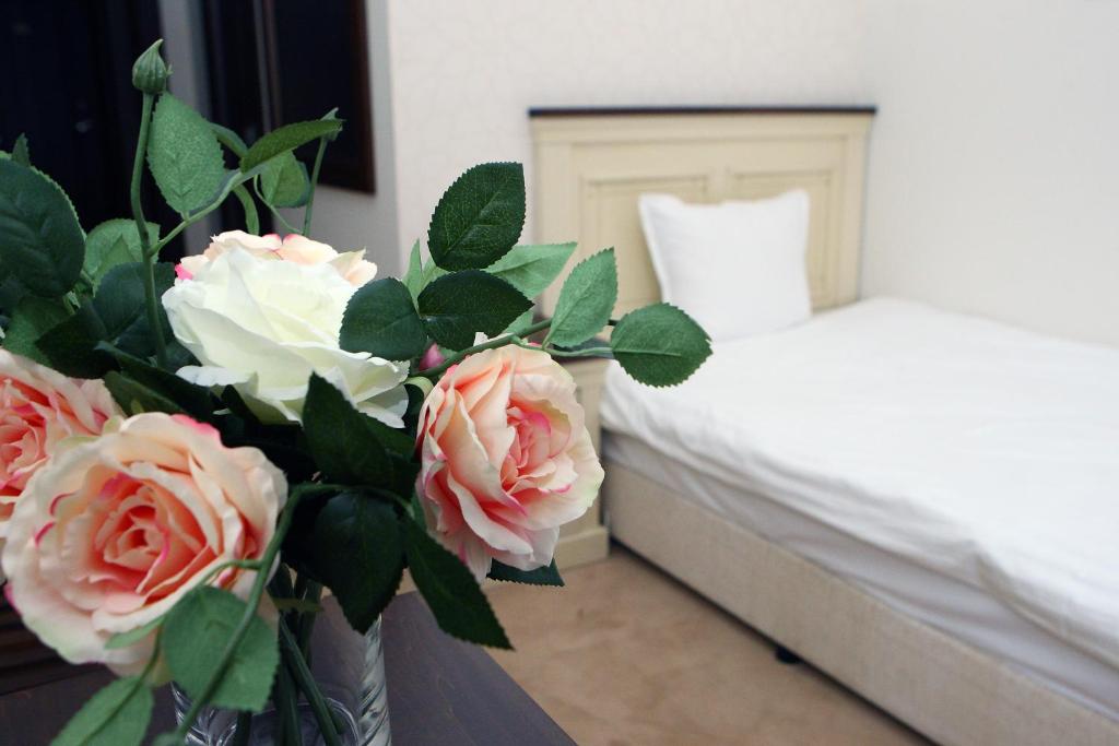 - une chambre avec un lit et un vase avec des roses dans l'établissement Hotel Par Avion, à Apriltsi