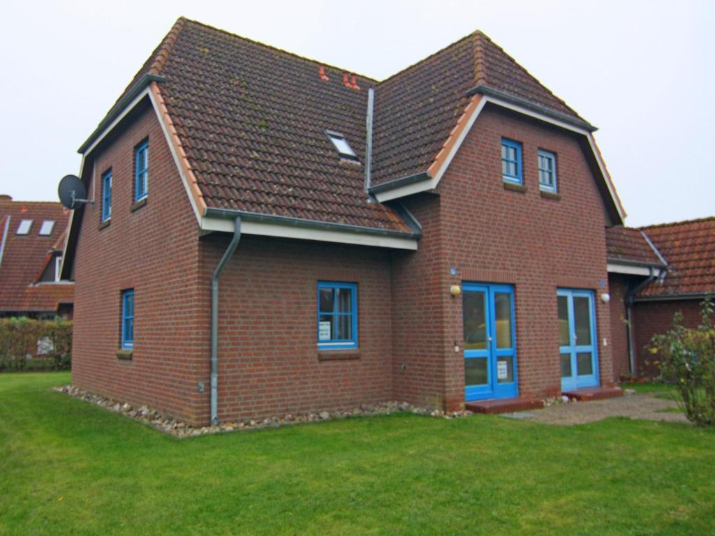 une maison en briques avec des fenêtres bleues et un toit dans l'établissement Cozy Holiday Apartment on Fehmarn, à Petersdorf auf Fehmarn